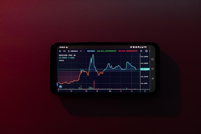 A phone against a maroon background showing a trading stock chart.