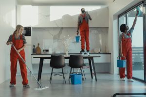 Person wearing gloves and cleaning a kitchen counter with a spray bottle and cloth.