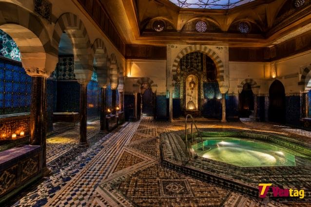 Historic Turkish Baths Harrogate interior with Moorish arches, blue tiled walls, mosaic floors, and warm Victorian lighting.