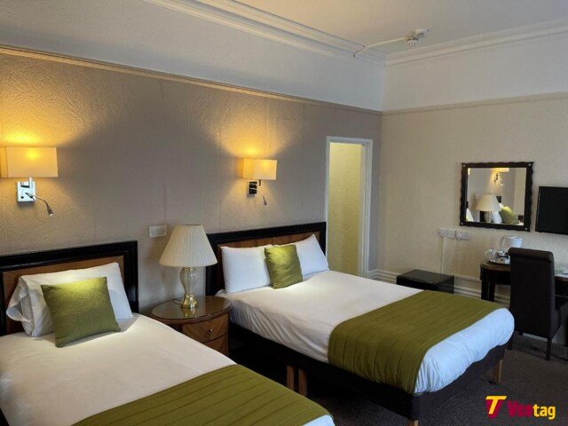 Twin bedroom at the Grand Scarborough with two comfortable beds, green bedding, bedside lamps, and modern room amenities.