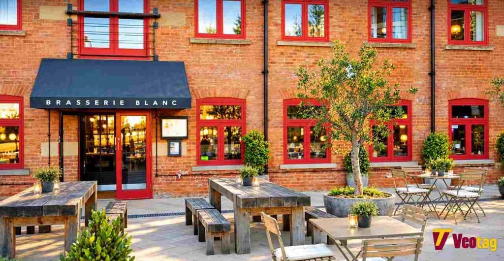 Brasserie Blanc Restaurant exterior with red brick walls, outdoor dining tables, and Veotag logo.