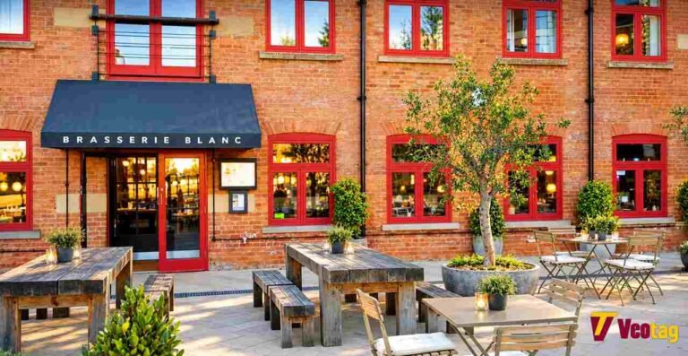 Brasserie Blanc Leeds: Menu, Location, Dining Experience and Booking Guide Brasserie Blanc Restaurant exterior with red brick walls, outdoor dining tables, and Veotag logo.
