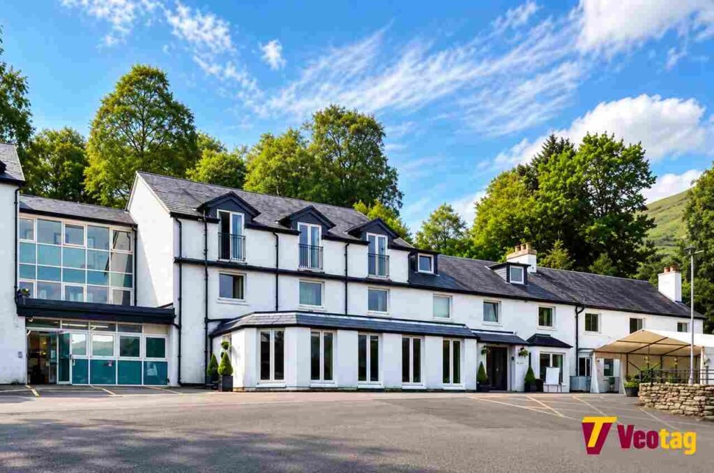 The Inn on Loch Lomond: Accommodation, Dining, Location and Visitor Guide The Inn on Loch Lomond hotel exterior with white walls, dark roofs, and surrounding green trees in Scotland.