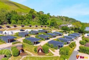 The Quiet Site: A Complete Guide to the Mysterious Website and Its Hidden Meaning A peaceful hillside campsite featuring modern cabins, wooden pods, green landscapes, and scenic mountain views.