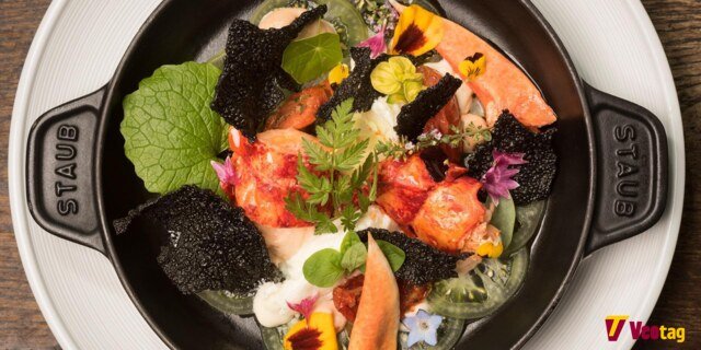 Gourmet lobster dish with fresh herbs, edible flowers, and crispy garnishes, showcasing fine dining at The Star Inn at Harome.